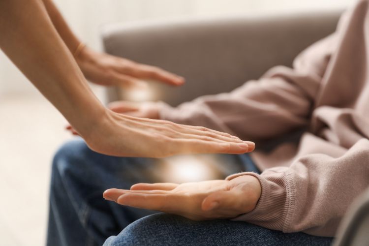 Reiki practitioner channeling healing energy above client’s hands.