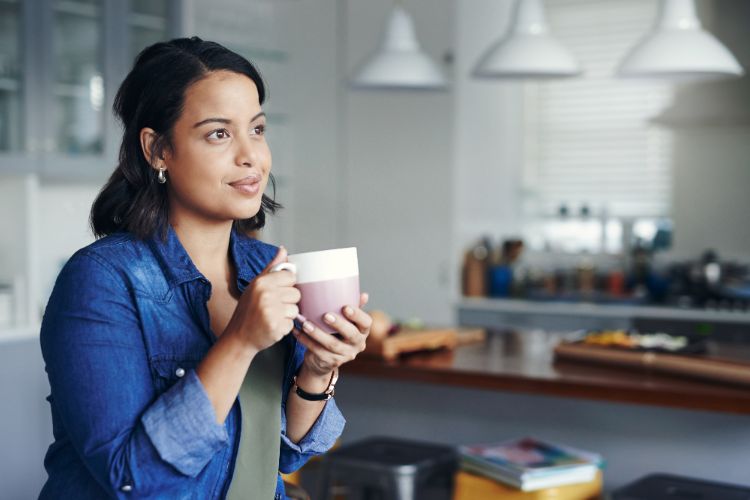 Woman reflecting on personal Reiki journey while holding a warm cup.
