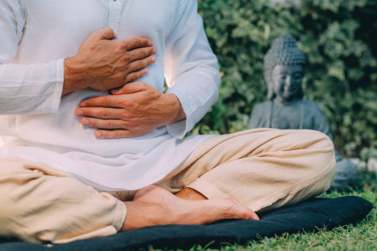 Man practicing Reiki self-healing meditation in a peaceful outdoor setting.
